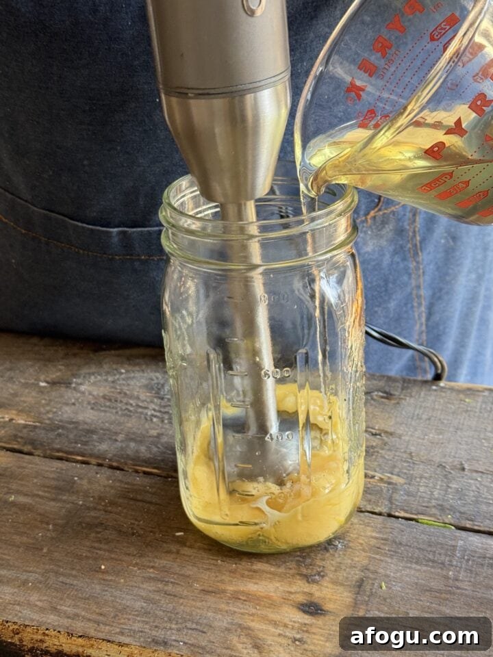 Creamy Chicken Cobb Salad Recipe with Avocado & Bacon 5 a photo adding oil into a jar with an egg and blender in it