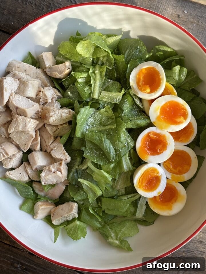 Creamy Chicken Cobb Salad Recipe with Avocado & Bacon 8 a photo of chicken and eggs on a bed of lettuce in a bowl