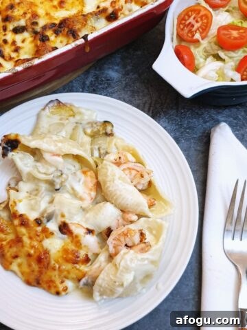 A plate of seafood stuffed pasta shells covered in cheese sauce.