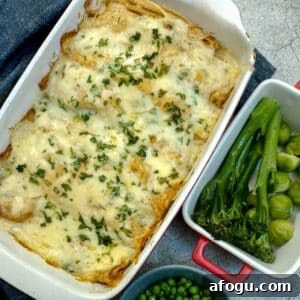 A dish of seafood-stuffed pancakes covered in cheese sauce and garnished with parsley.