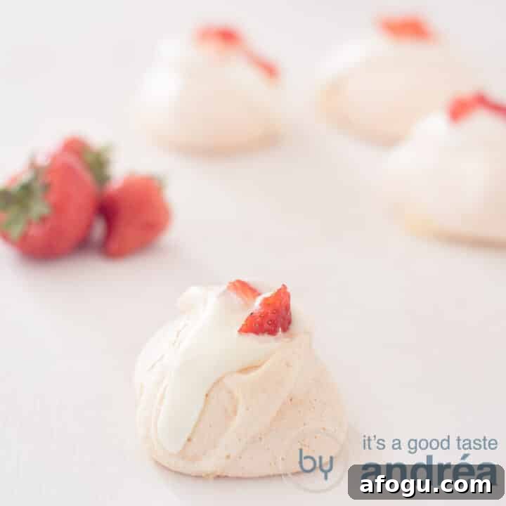 A square photo with rose meringue in the foreground and three in the background. Left strawberries.