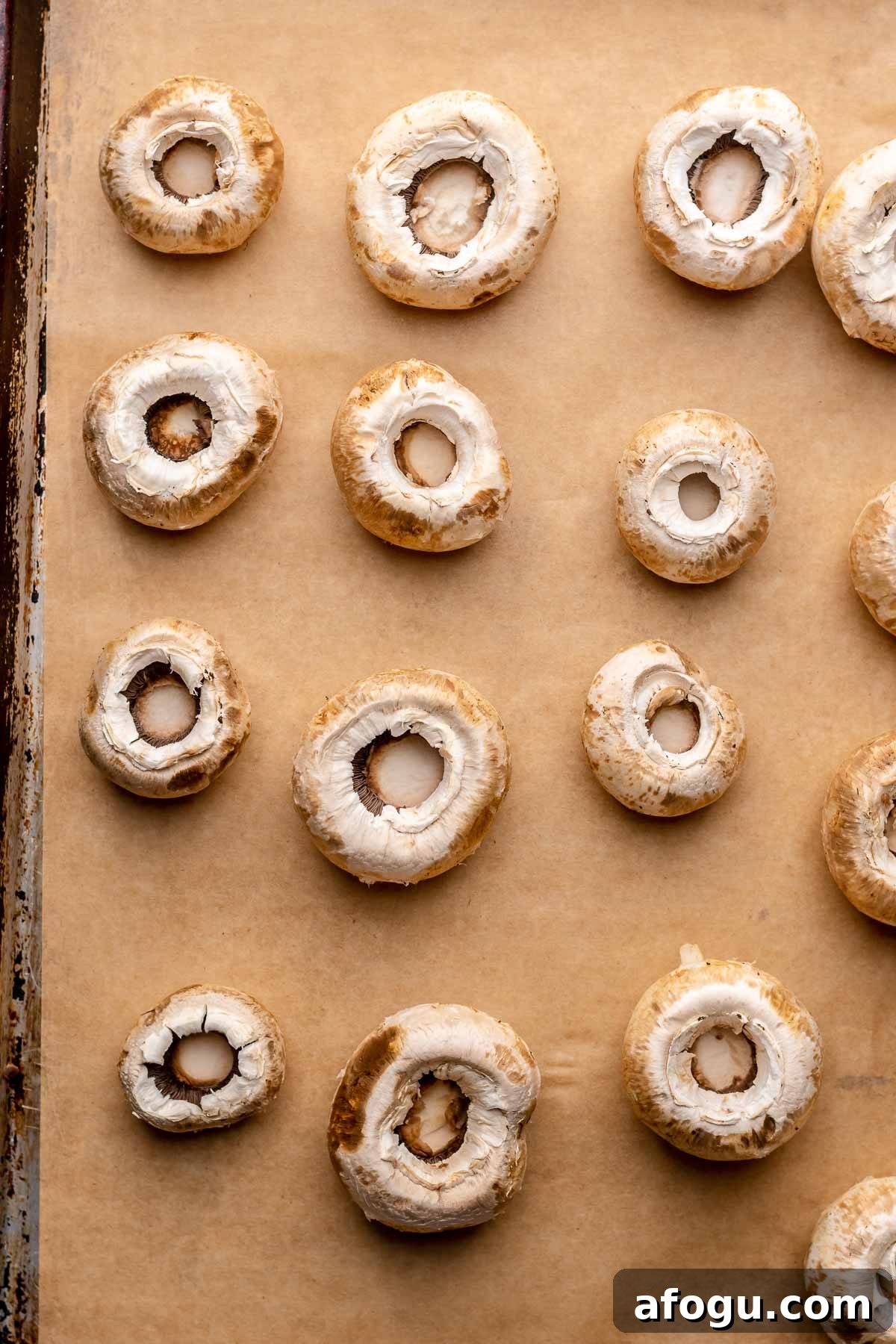Mushroom caps on a sheet pan with stems removed.