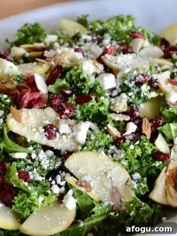 Kale Cranberry Feta Salad with almonds and apples in a white serving platter.