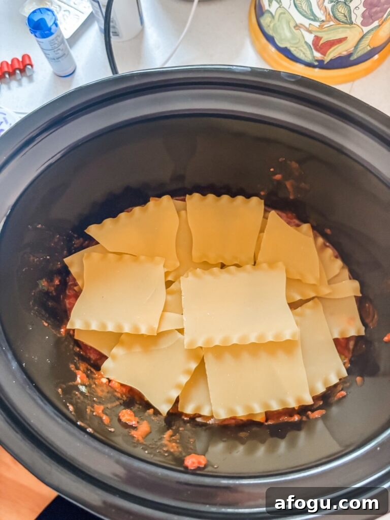 The broken up, no boil lasagna noodles placed in the slow cooker