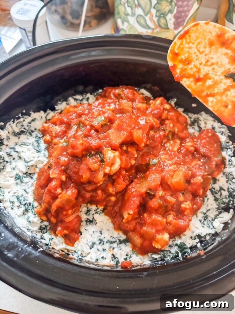 The sauce and cheese mixture being layered into the slow cooker
