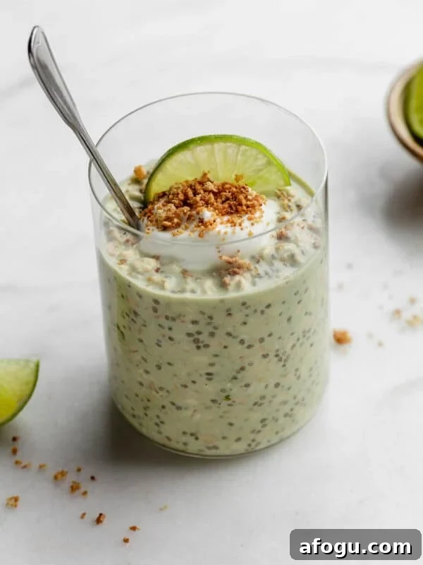 Key lime pie overnight oats topped with yogurt and graham cracker crumbs with a spoon in it.