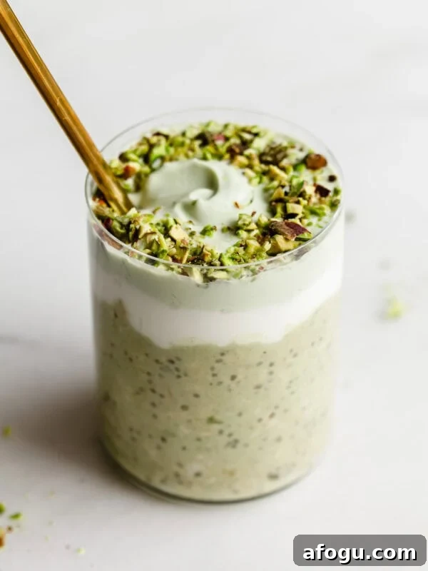 a cup of pistachio overnight oats with yogurt and crushed pistachios on top.