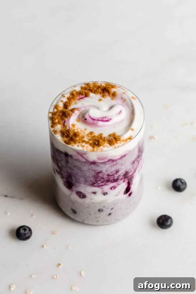 Blueberry overnight oats in a jar on a white marble counter with blueberries around it.