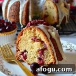white chocolate cranberry bundt cake slice on white plate with gold fork