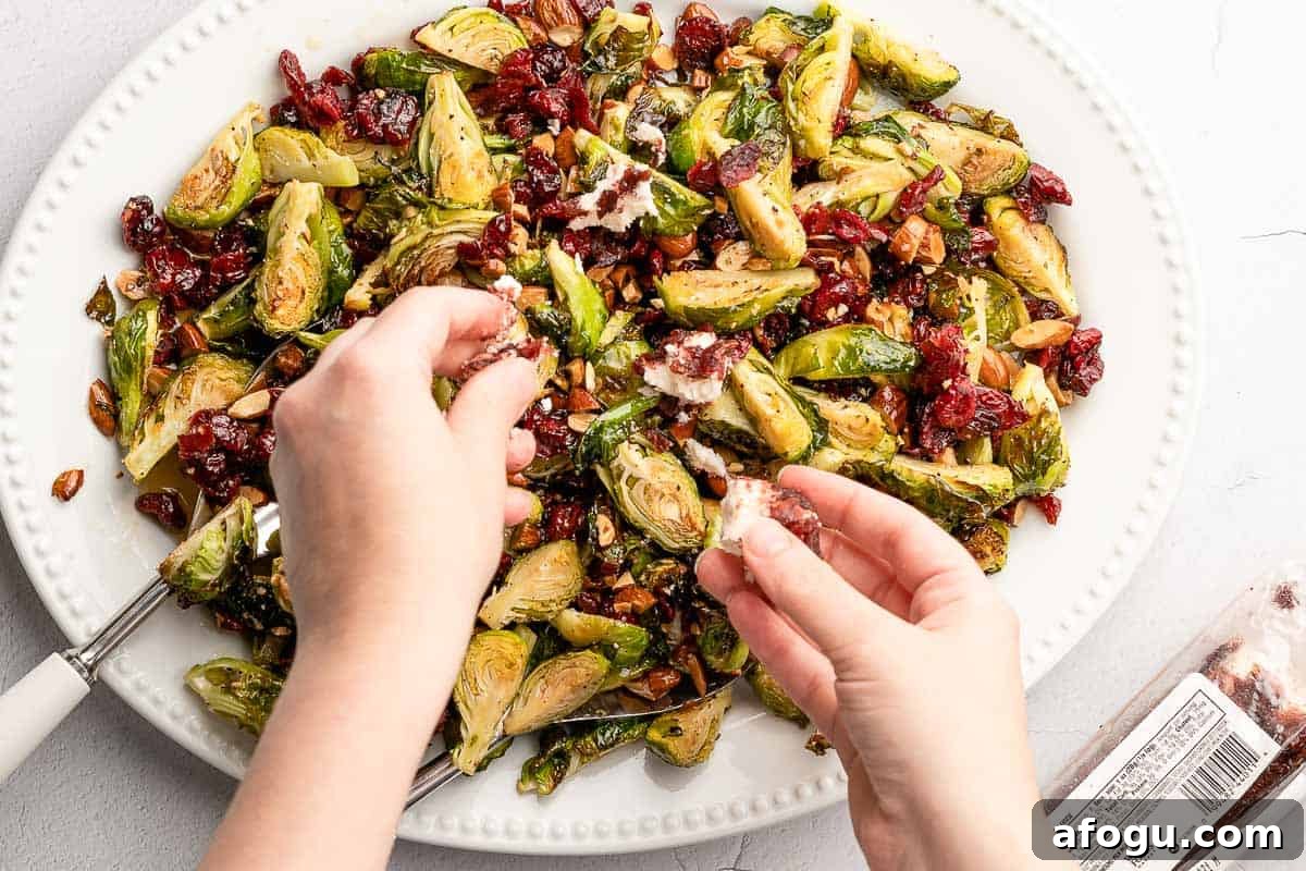 hands crumbling cheese overtop salad on platter