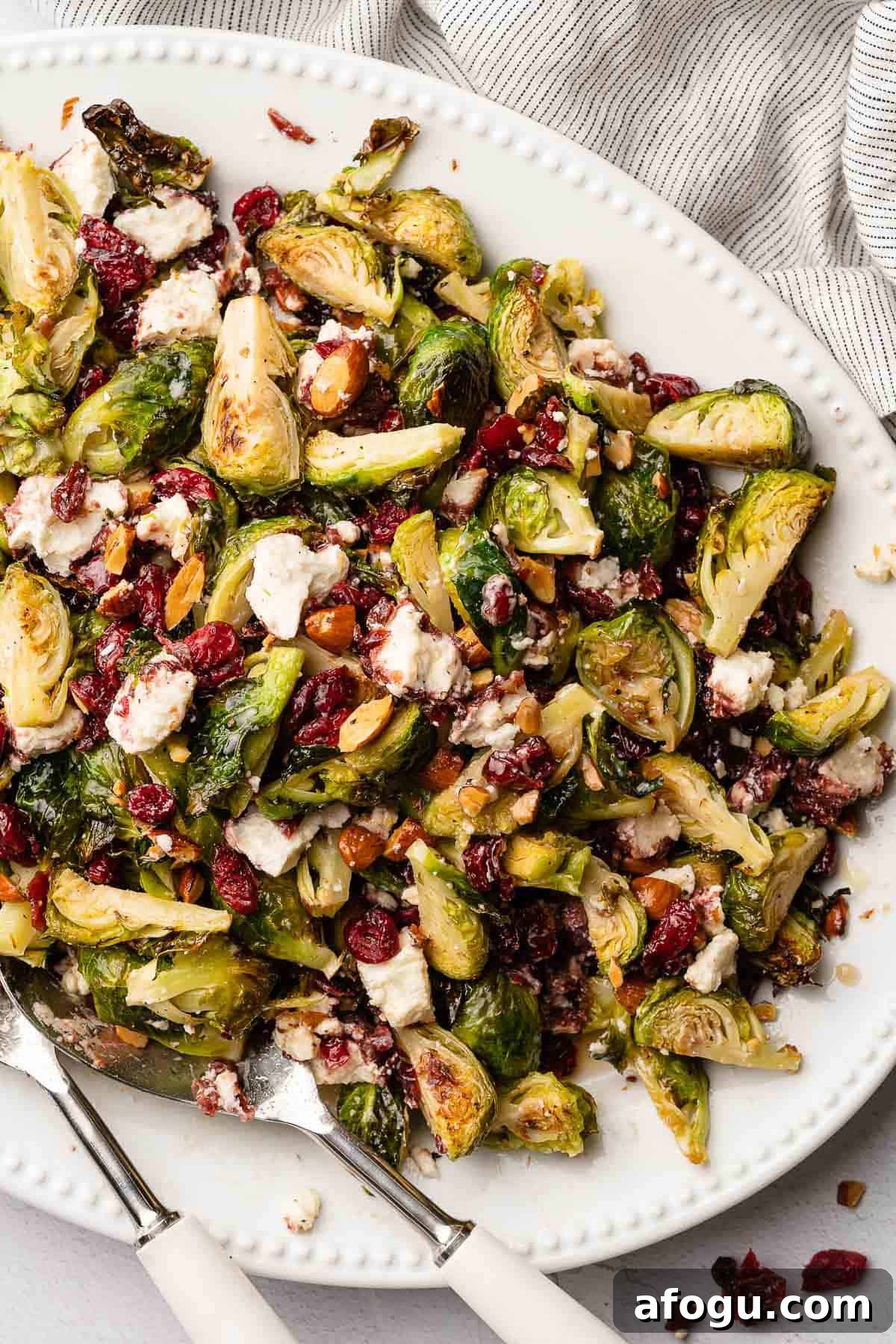 brussels sprouts salad with cranberries on white platter with napkin in background