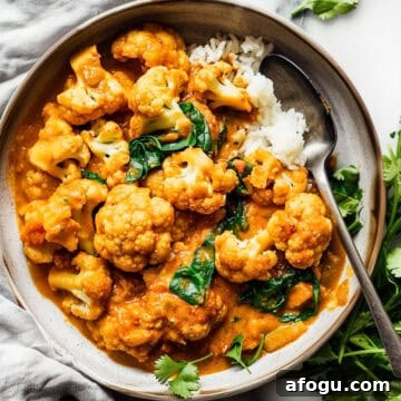 Cauliflower curry with spinach and rice in a bowl with coriander.