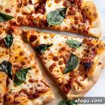 Margherita pizza with basil and mozzarella on a marble table.