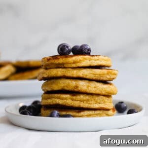 6-Ingredient Cottage Cheese Oatmeal Pancakes Recipe 15 stack of pancakes on a white plate with blueberries on top