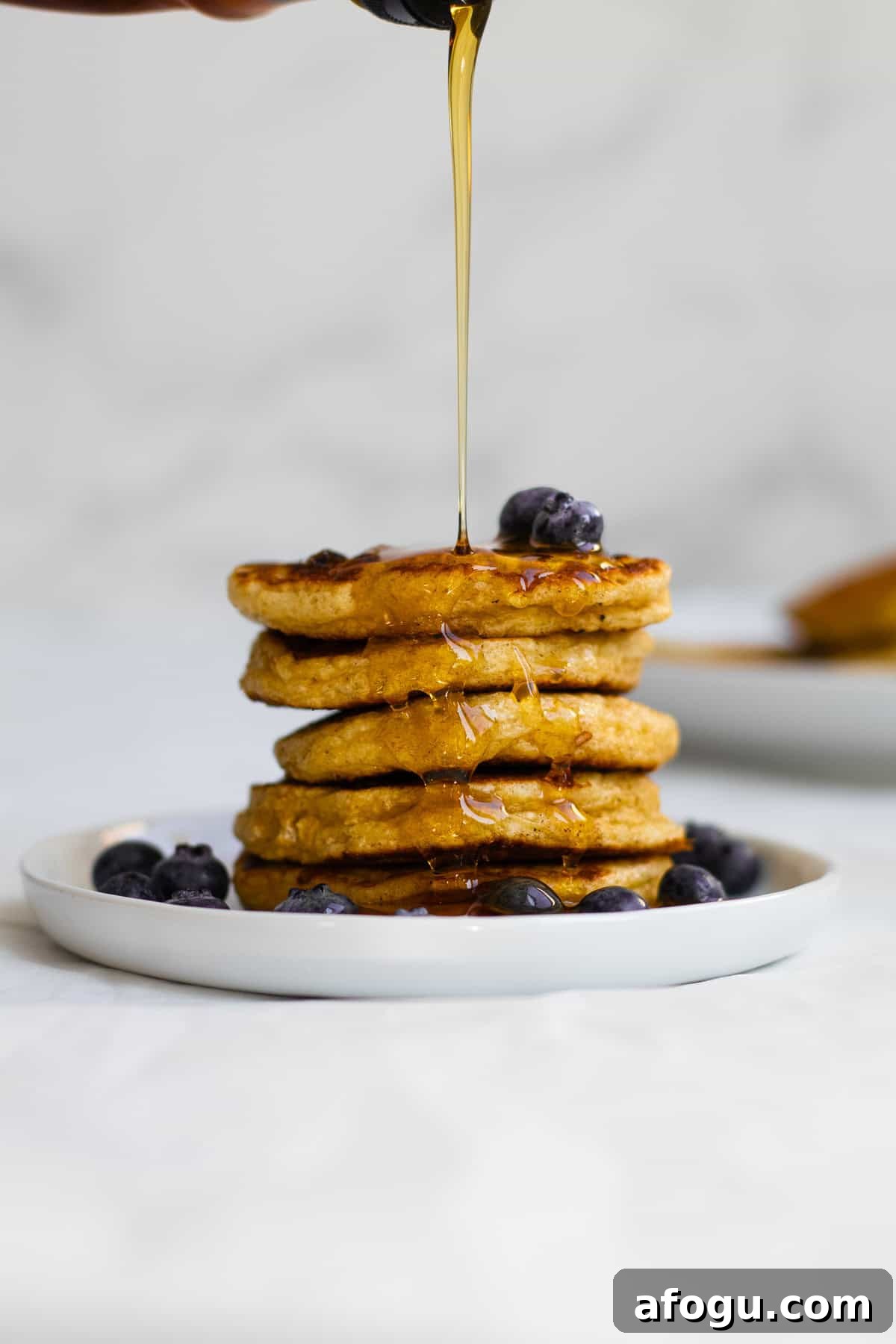 6-Ingredient Cottage Cheese Oatmeal Pancakes Recipe 9 syrup being poured over a stack of pancakes
