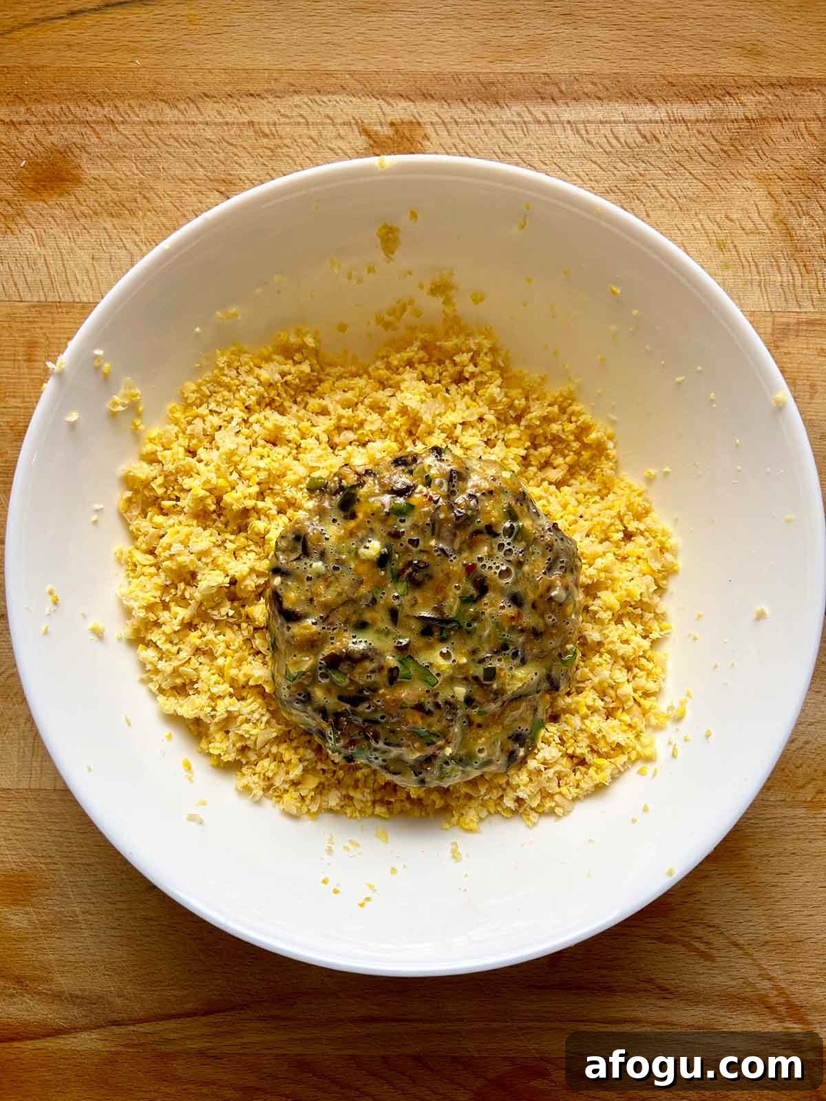 patty in bowl of chickpea breadcrumb mixture