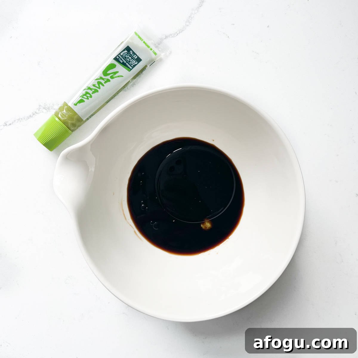 Adding soy sauce to a white bowl for the sushi salad dressing.