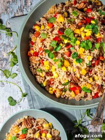 A large bowl with brown rice salad with a smaller bowl next to it.