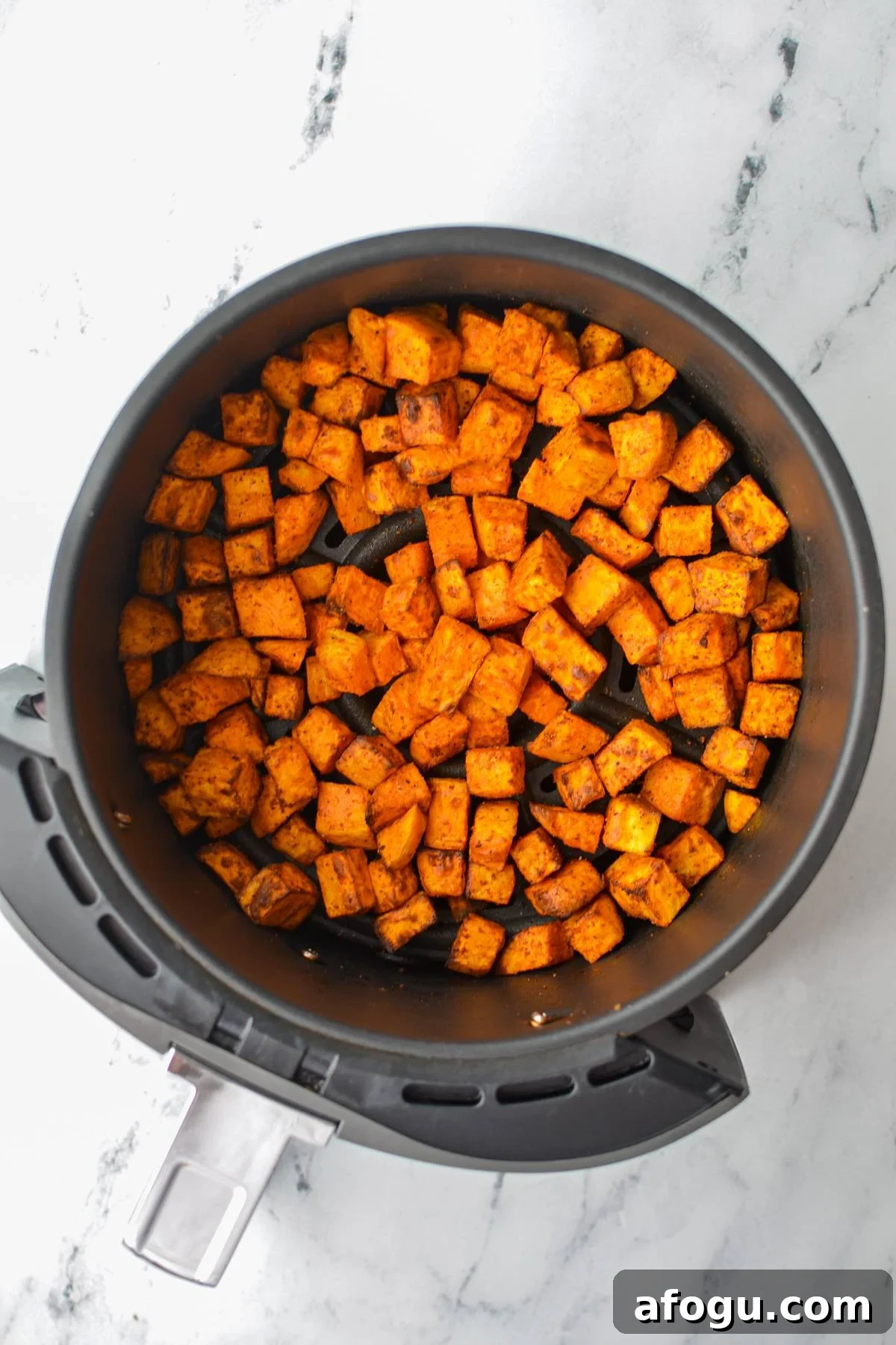 Crispy Air Fryer Sweet Potato Cubes Recipe 9 An air fryer basket with roasted sweet potato chunks.