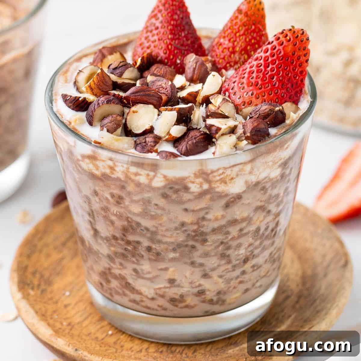 Glass jar of overnight oats, topped with yoghurt, crushed hazelnuts and cut strawberries.