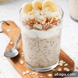Glass jar of overnight oats, sitting on a wooden board, with a spoon on the edge.