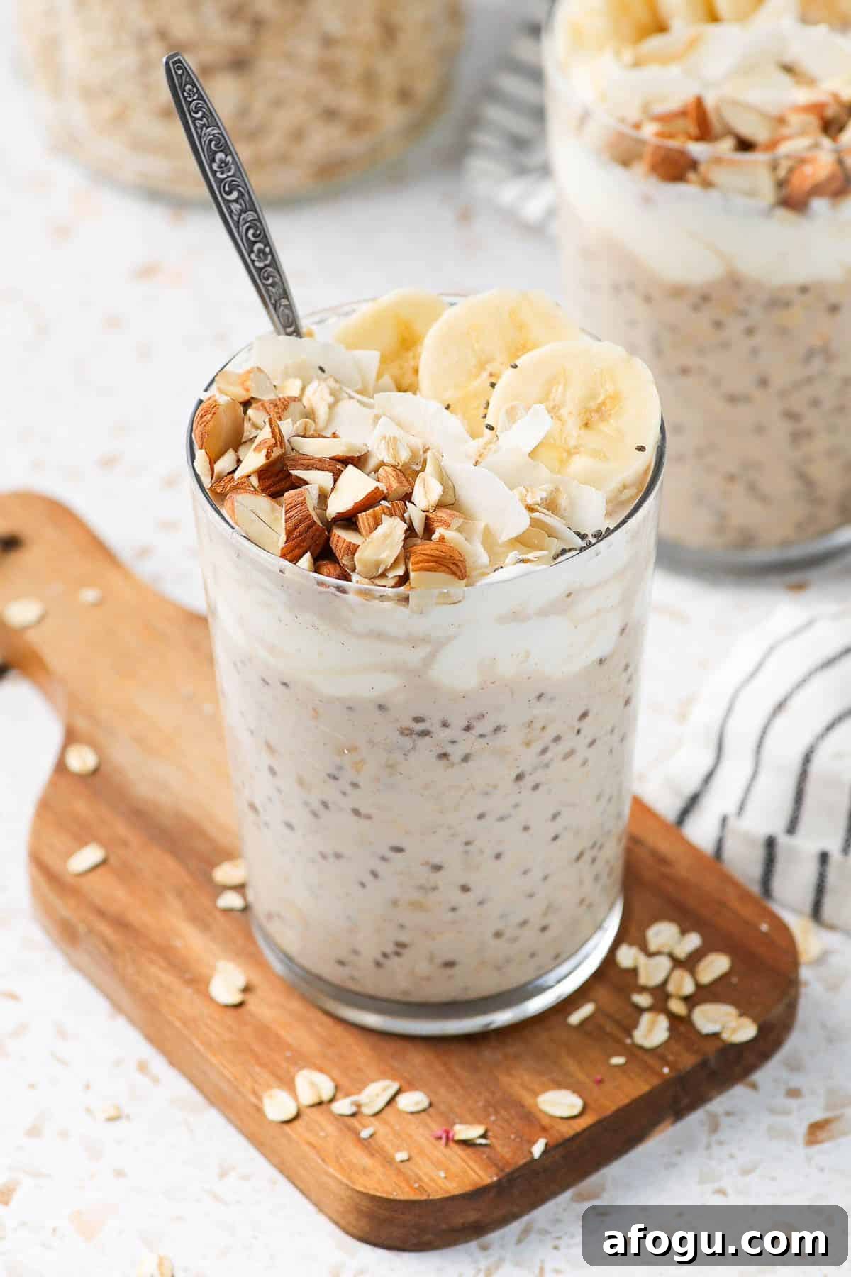 Glass jar of overnight oats, sitting on a wooden board, with a spoon in the jar.