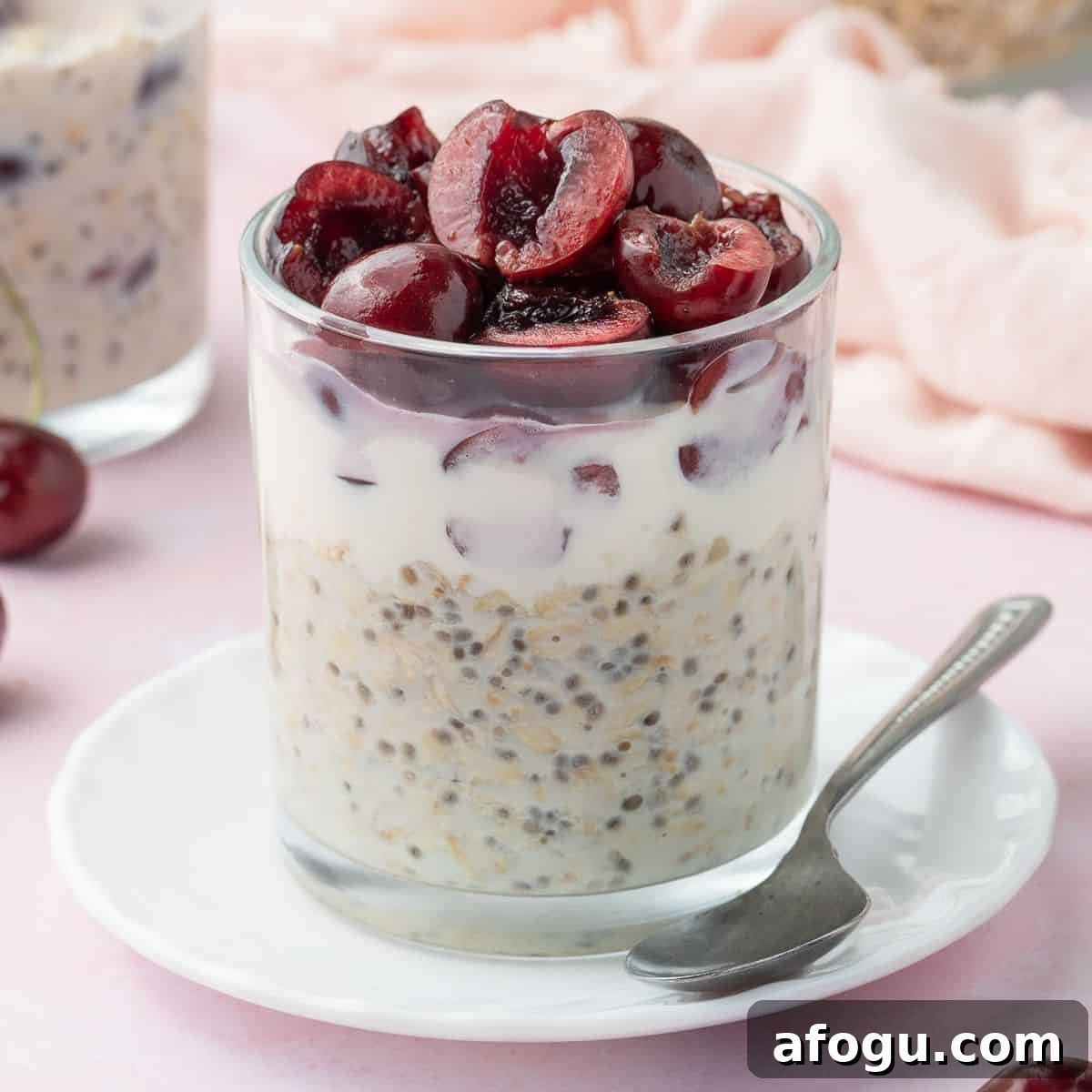Glass jar of vanilla overnight oats, topped with halved cherries.