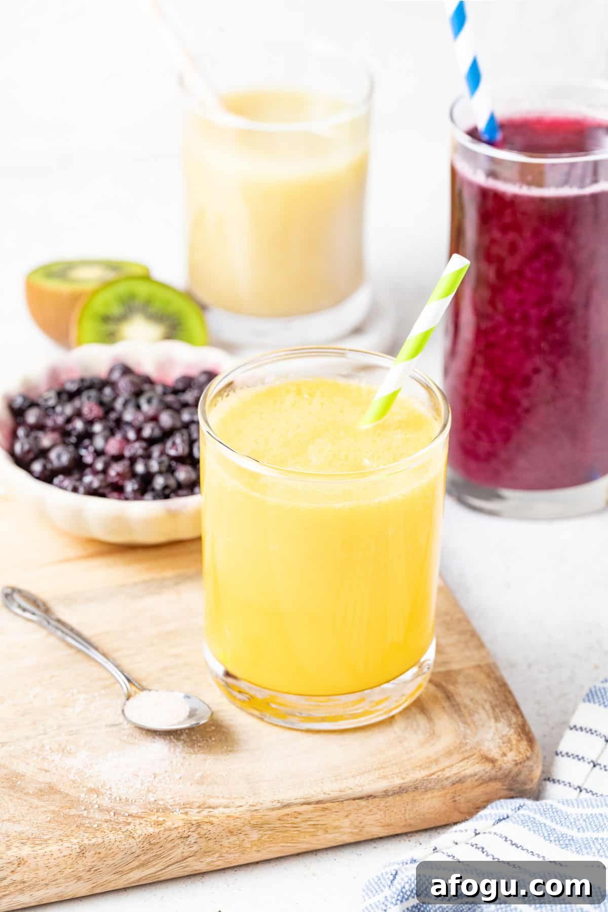 Mango electrolyte drink in a glass next to berries.