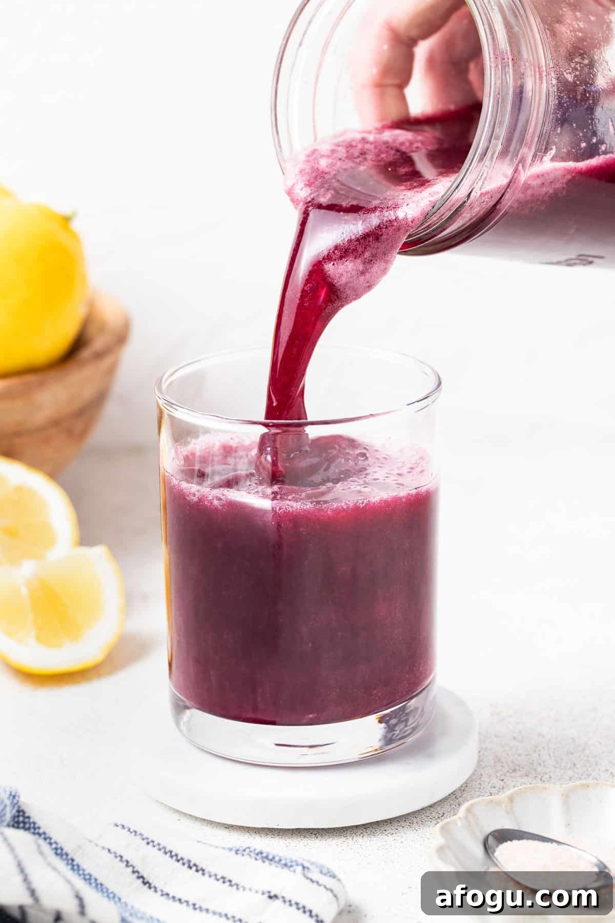 Pouring the blueberry gatorade mixture into a clear glass.
