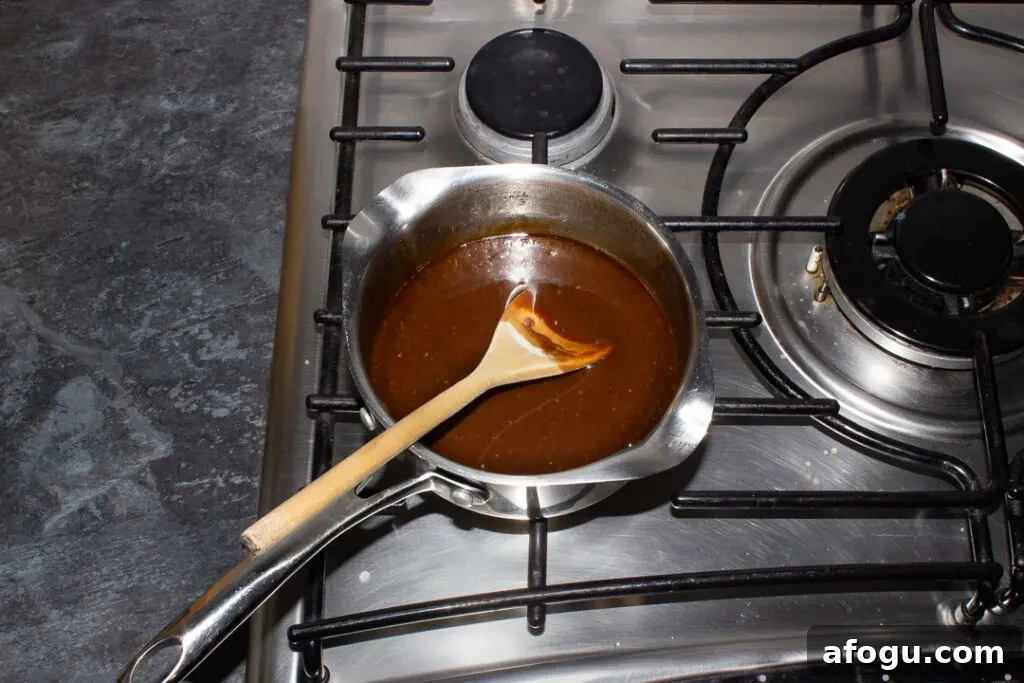 Classic Gingerbread Biscuit Recipe for Perfect Holiday Baking 9 A small saucepan filled with a melted mixture of dark muscovado sugar, unsalted butter and golden syrup set on a stove top.