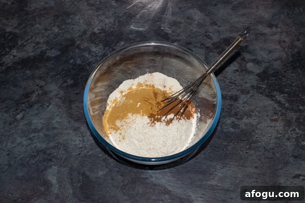 Classic Gingerbread Biscuit Recipe for Perfect Holiday Baking 10 A large mixing bowl filled with ginger, cinnamon and flour on a kitchen worktop.