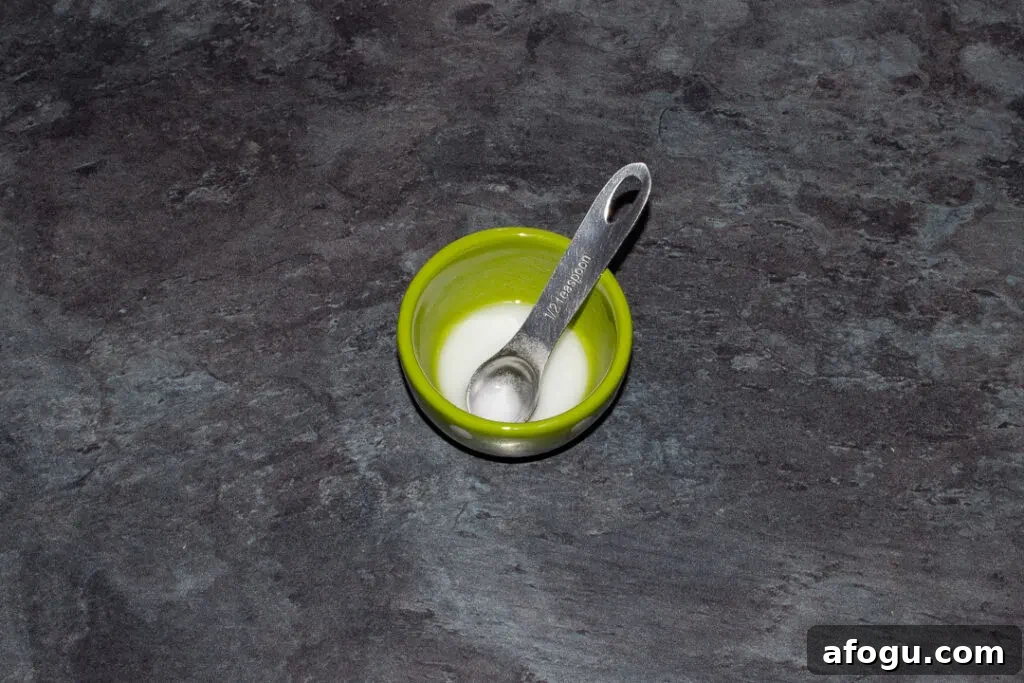 Classic Gingerbread Biscuit Recipe for Perfect Holiday Baking 11 A small green pot filled with bicarbonate of soda dissolved in water set on a kitchen worktop.