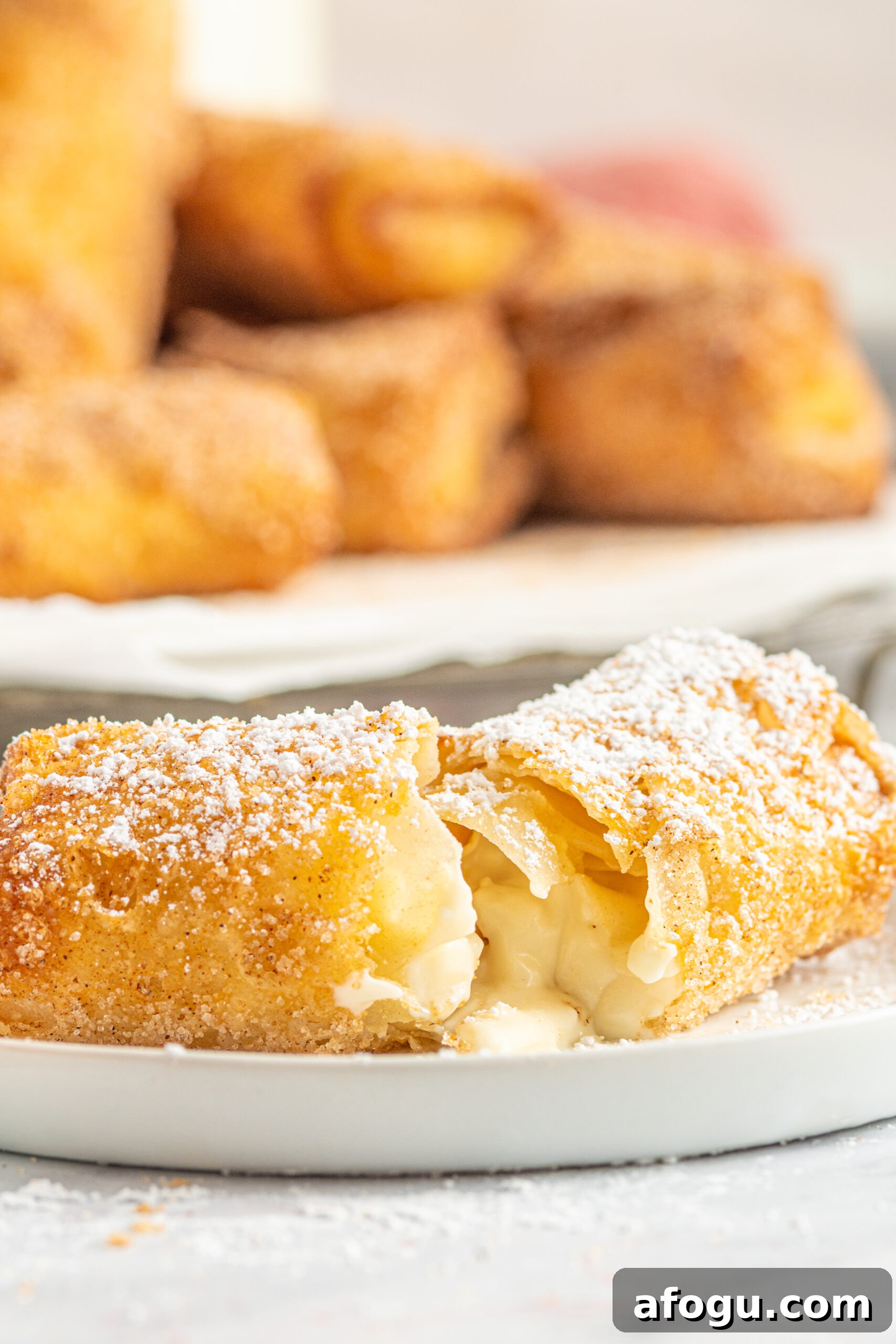 Side view of a Cheesecake Egg Roll split in half on a white plate.