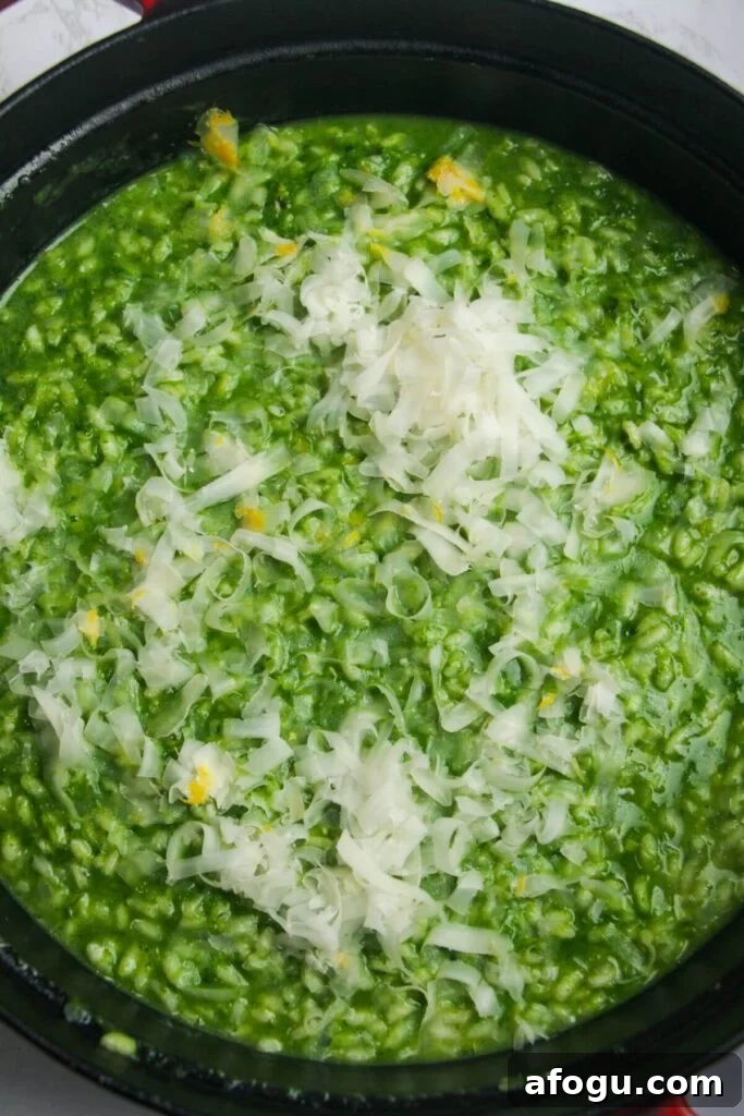 Grated parmesan on top of wild garlic risotto in a large black skillet.