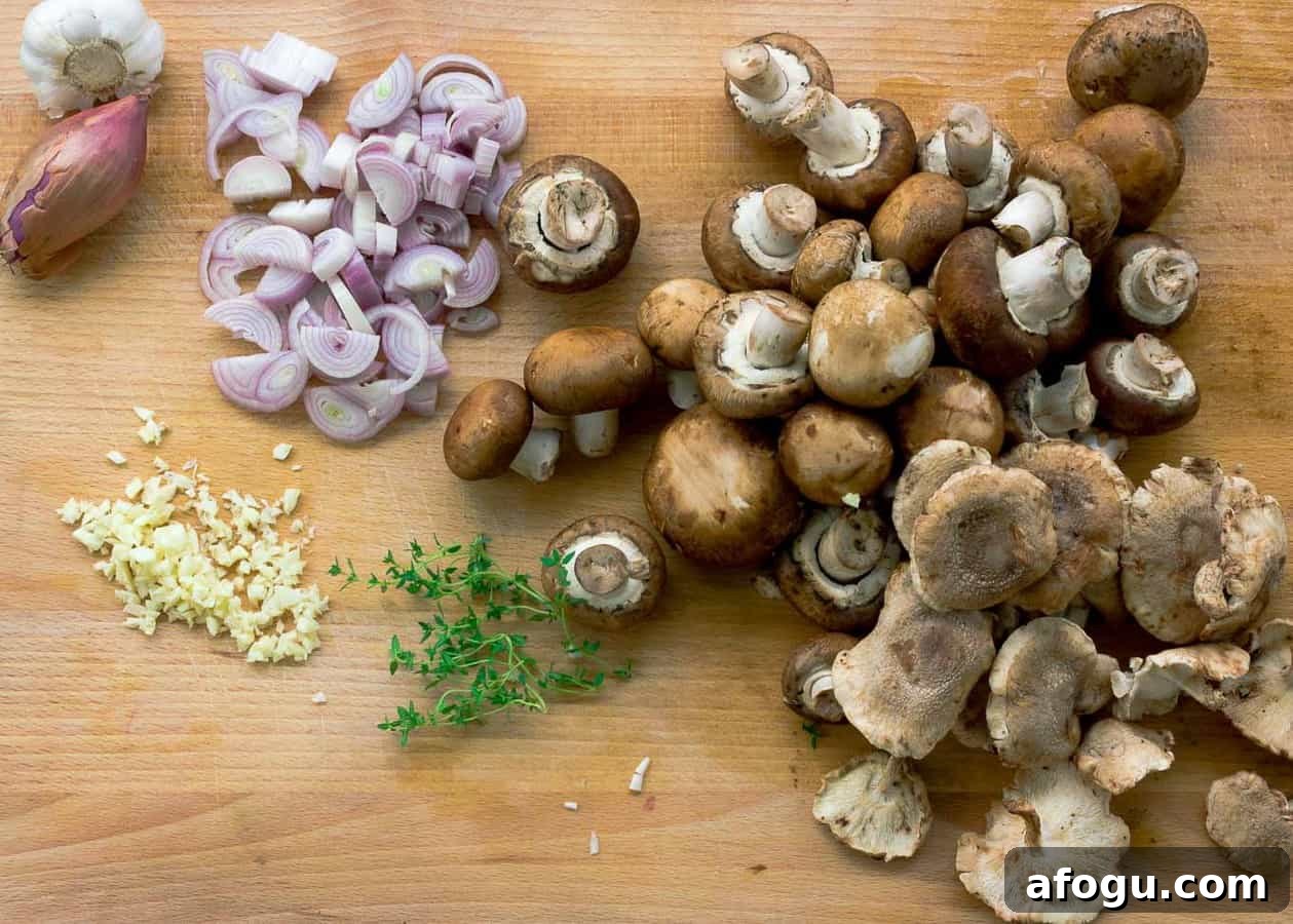 Prepping for Crispy Roasted Chicken with Mushrooms and Cream. Cutting board with shallots, garlic, mushrooms, and thyme being sliced.
