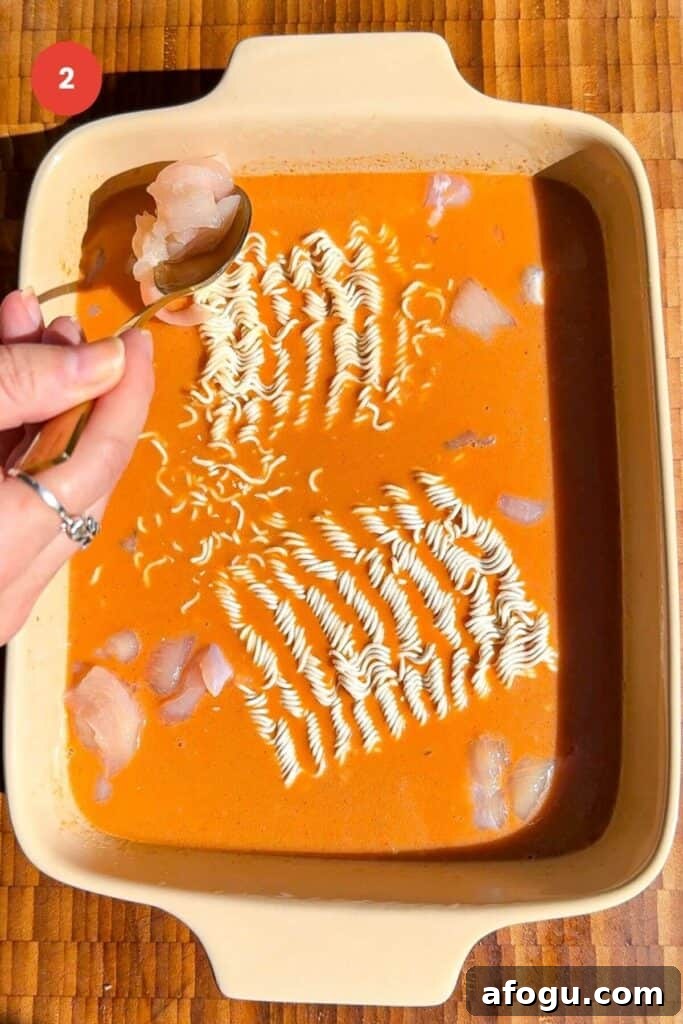Ramen cakes in satay sauce in an oven dish, with diced chicken.