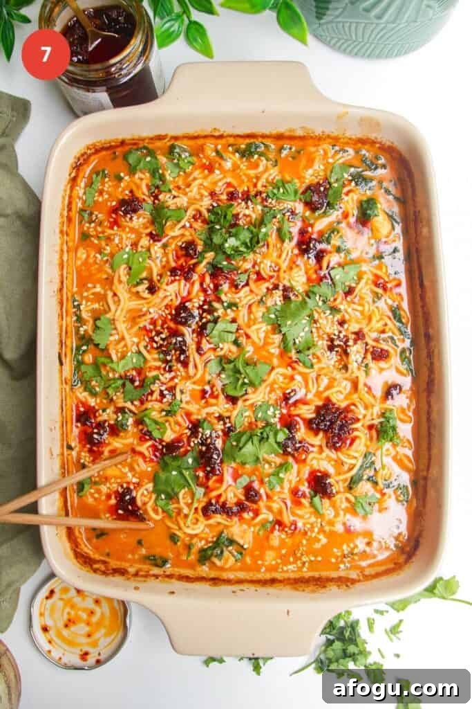 Baked satay ramen in an oven dish, topped with chili oil and cilantro.
