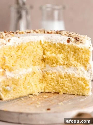 Almond cream cake on a cake stand with slices taken out of it.