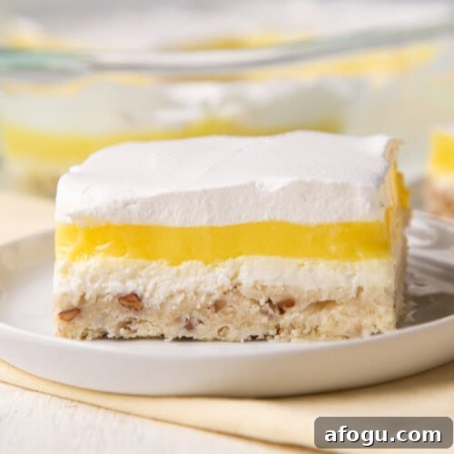 four layer lemon dessert on a white plate.