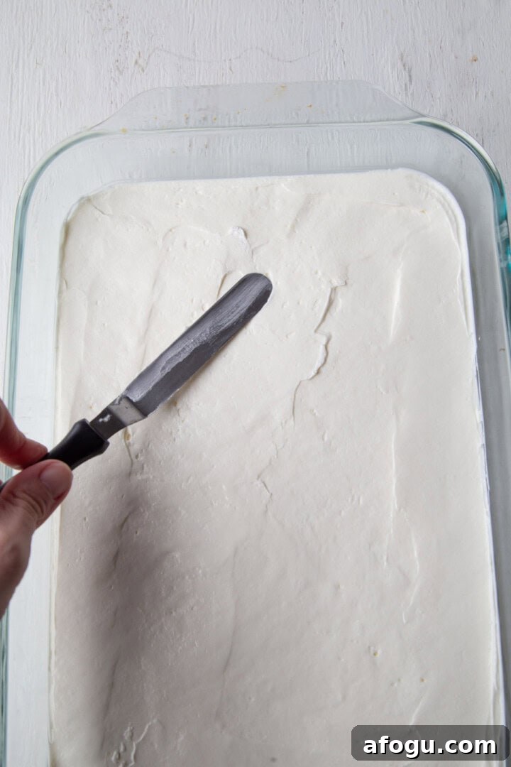 spatula spreading a white filling into a baking dish.