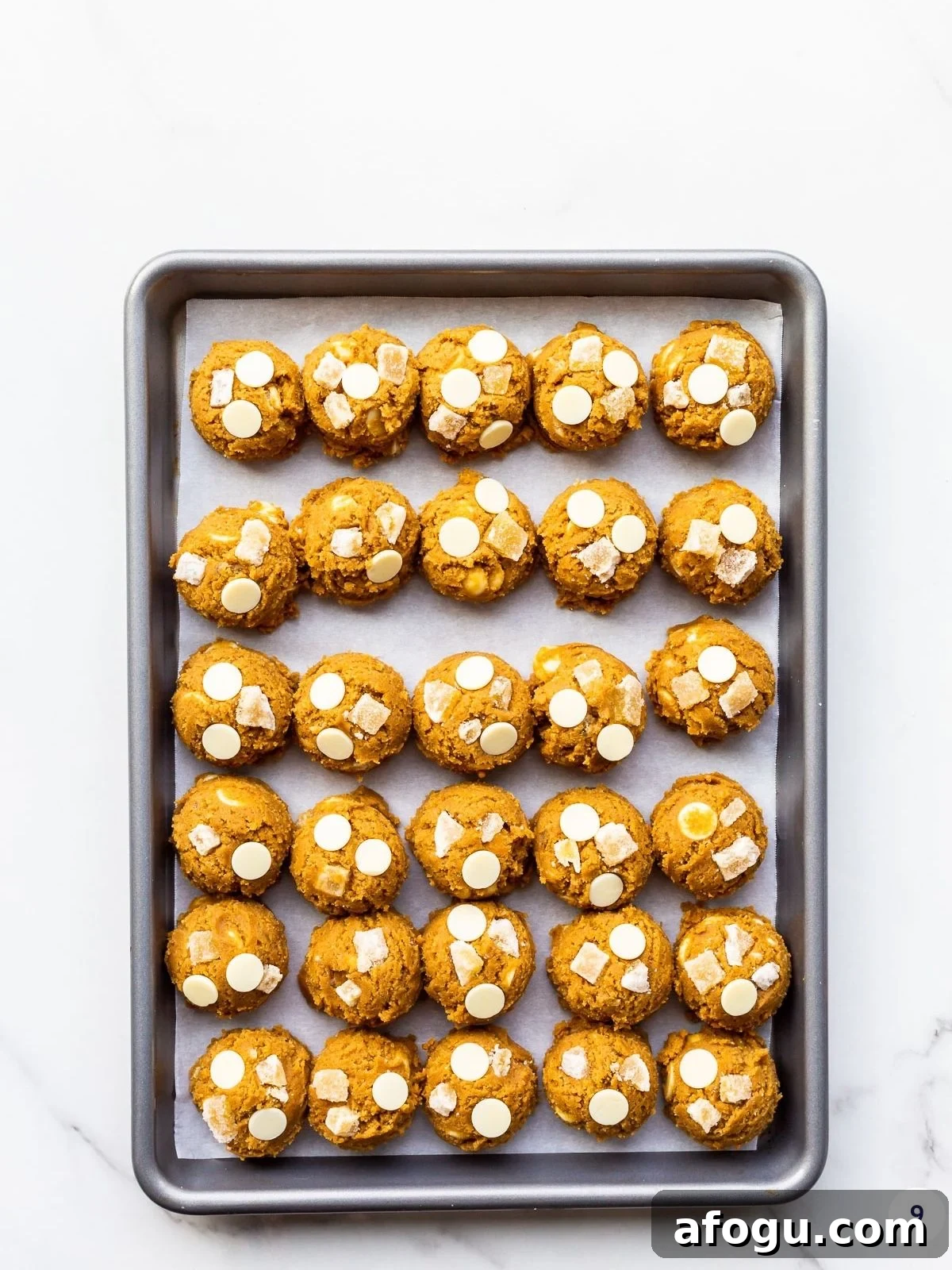 Portioned out scoops of ginger cookie dough with white chocolate chips and crystallized ginger.