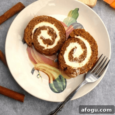 Two slices of pumpkin roll cake on a plate with a fork.