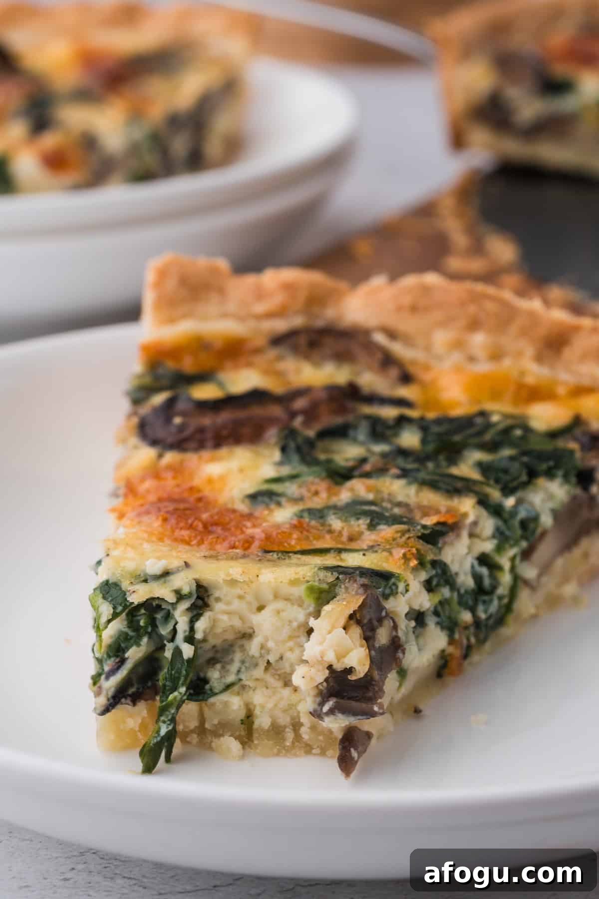 Spinach Mushroom Quiche Recipe — Flaky Crust, Creamy Filling 2 A slice of a spinach quiche with mushrooms.