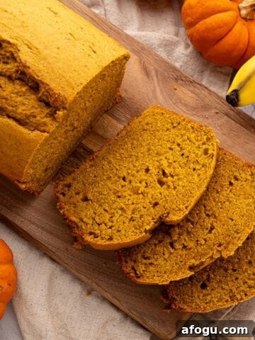 Sliced banana bread with pumpkin on a cutting board.