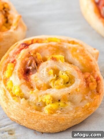 Close-up of freshly baked breakfast pinwheels with scrambled eggs, salsa and cheese.