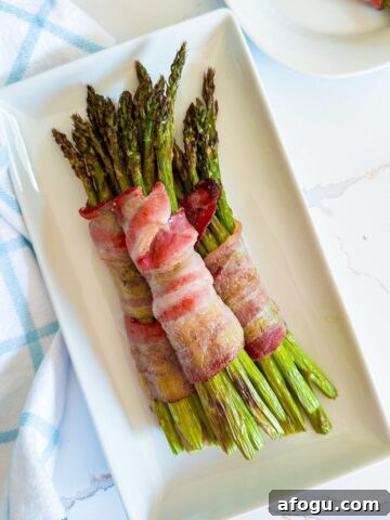 Bundle of air fryer bacon wrapped asparagus on a plate.