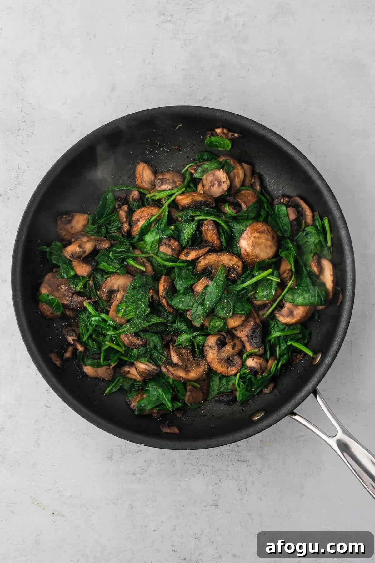 Spinach Mushroom Quiche Recipe — Flaky Crust, Creamy Filling 5 Cooked mushrooms and wilted spinach in a pan.