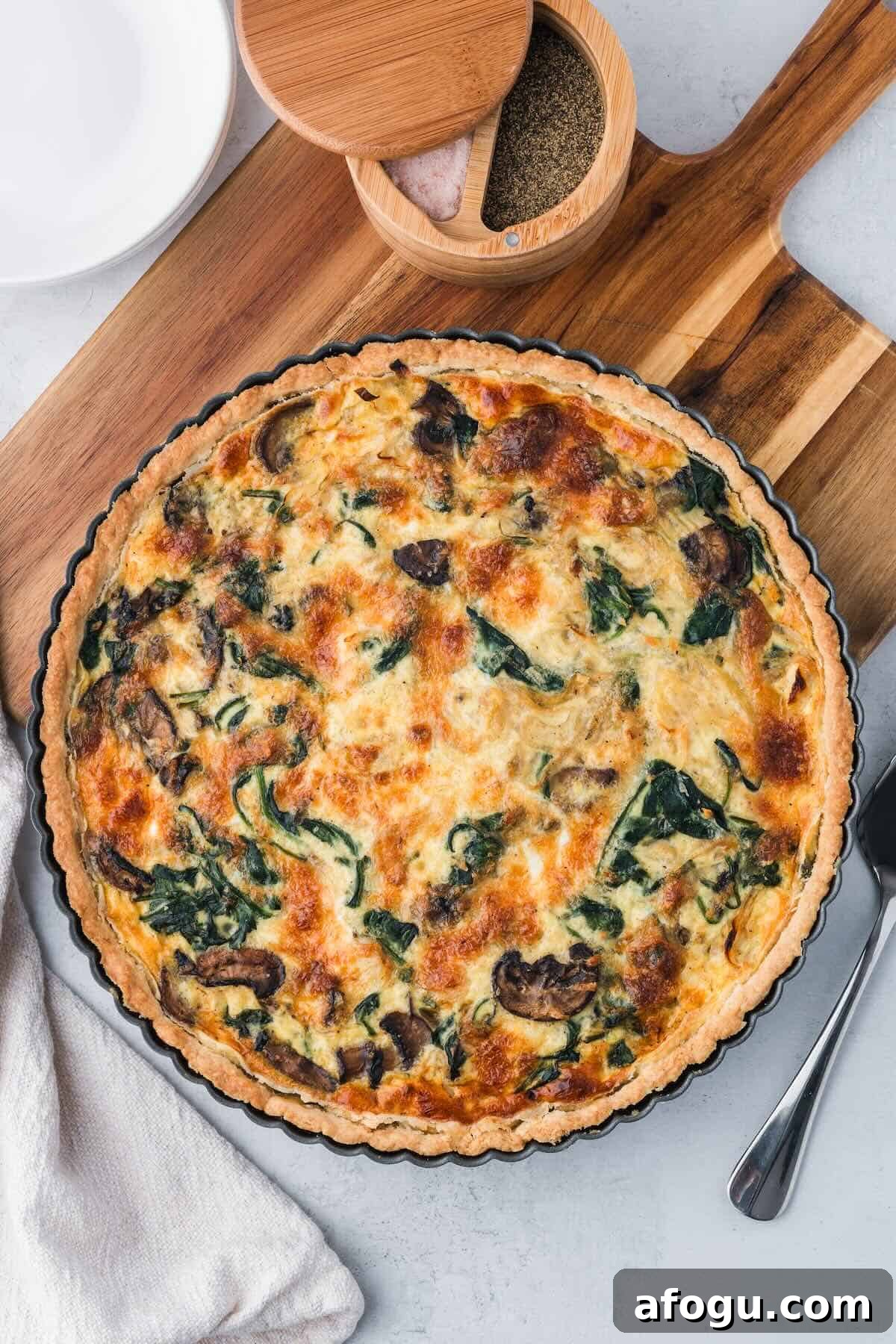 Spinach Mushroom Quiche Recipe — Flaky Crust, Creamy Filling 9 A baked quiche with spinach and mushrooms in a tart pan.