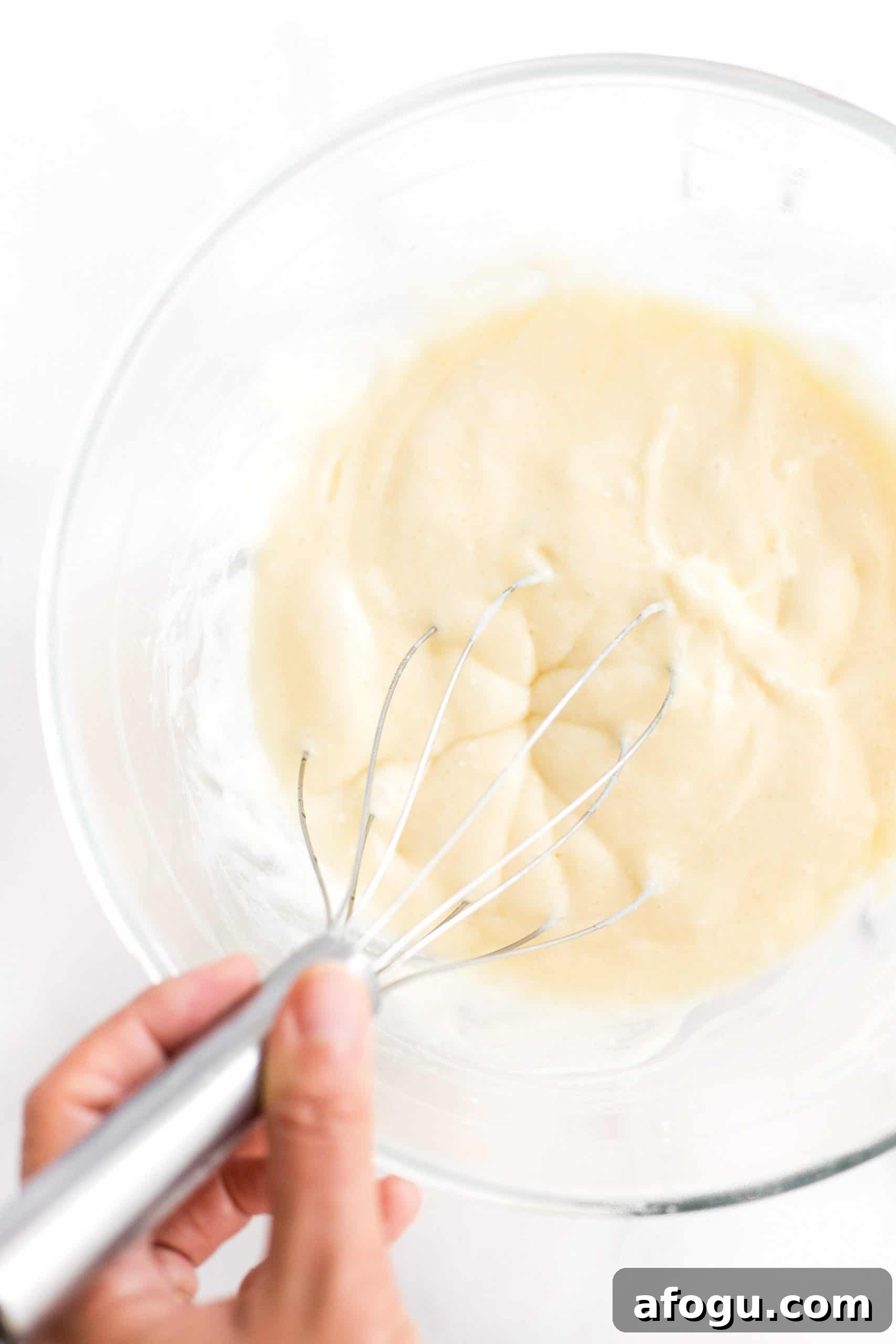 Easy Gluten-Free Peach Cobbler (Dairy-Free, Vegan) Whisking batter in a glass bowl.