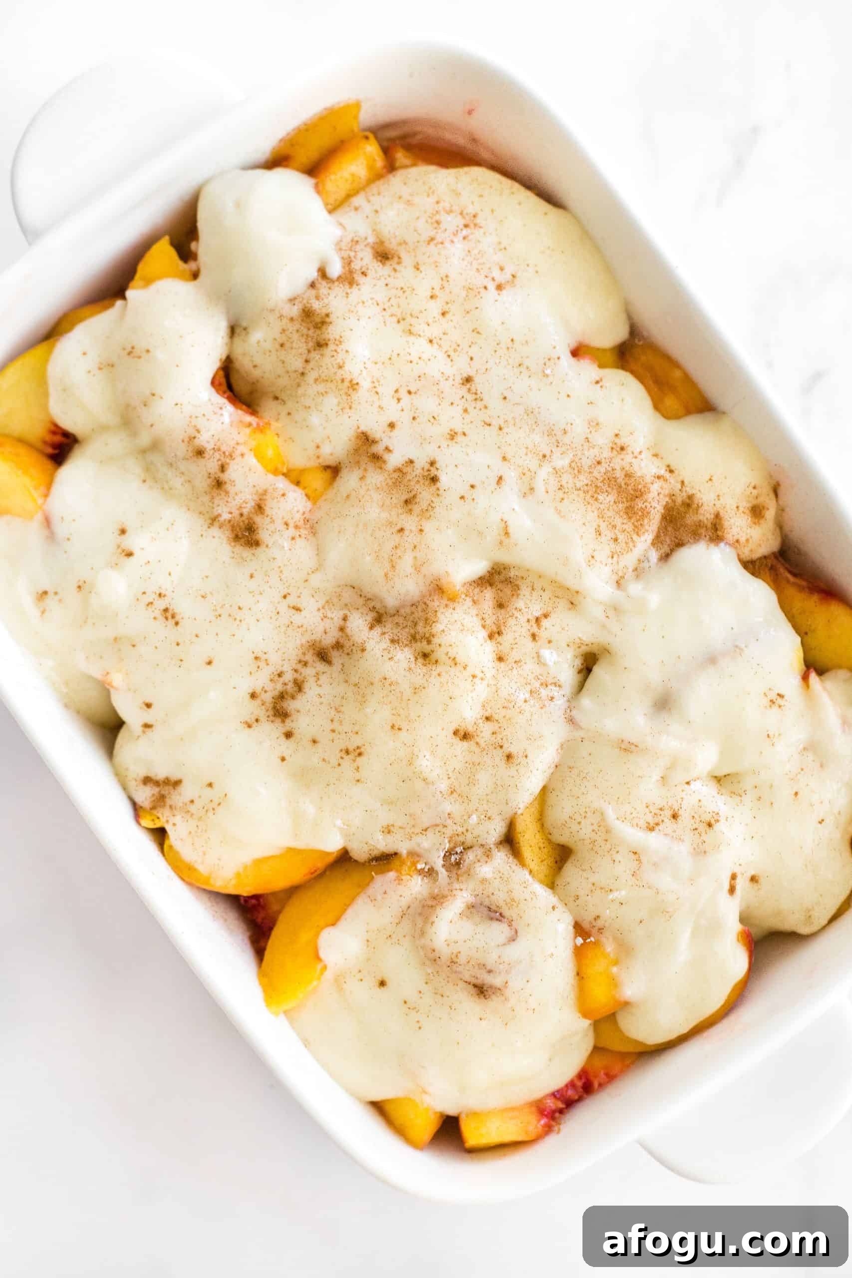 Easy Gluten-Free Peach Cobbler Recipe (Dairy-Free, Vegan) Cobbler topping on top of peach slices in a baking dish.